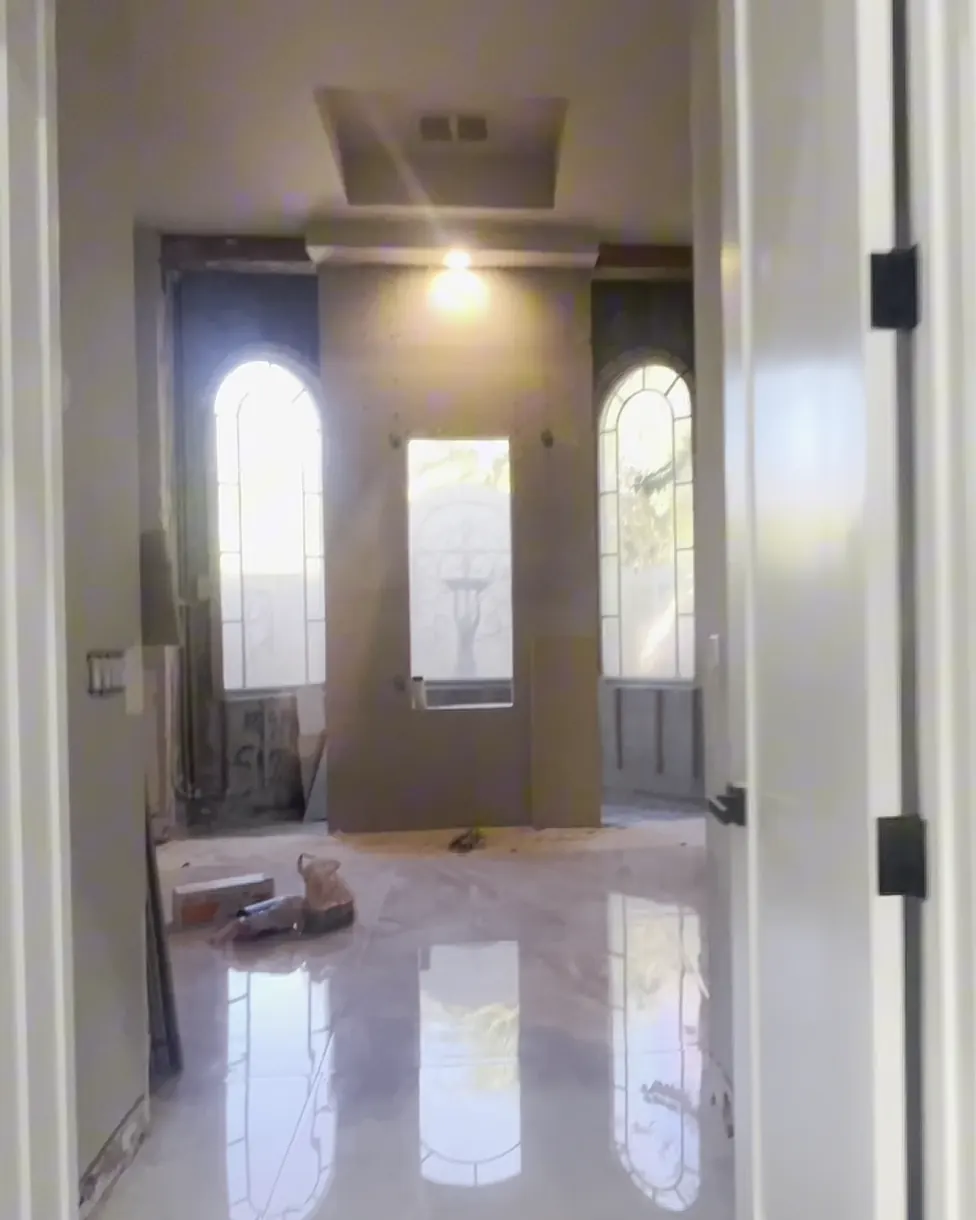 View through the doorway into the bathroom mid-job, with bare walls and three windows