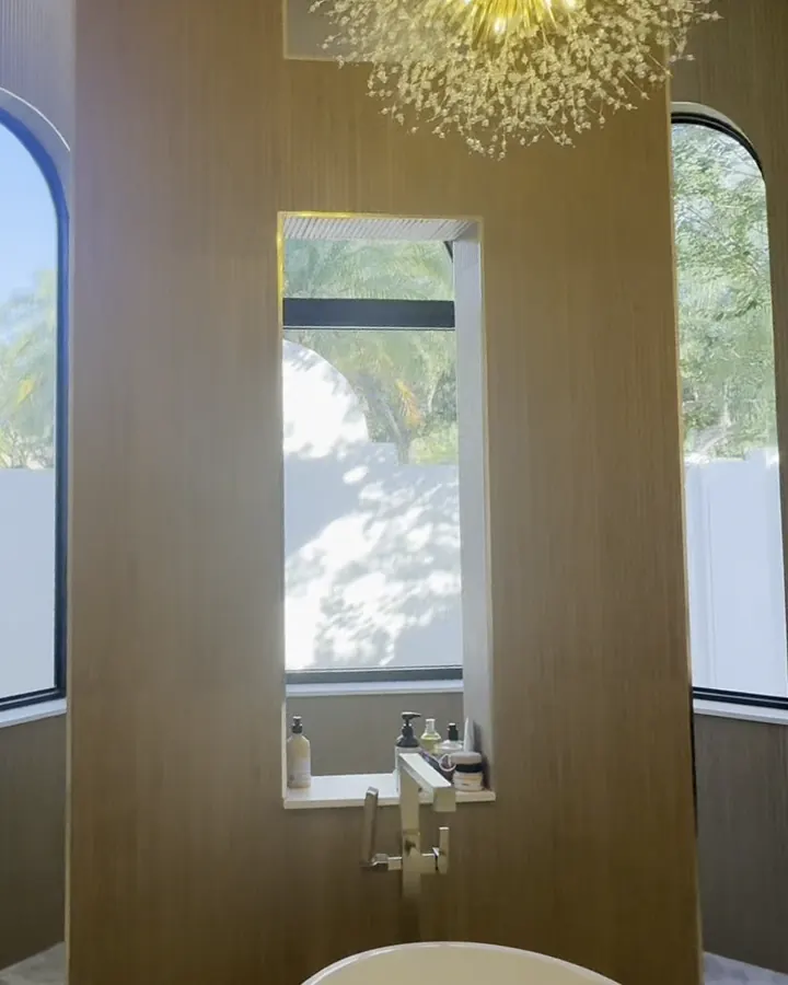 The same wall finished, with wood slat panels, a gold chandelier and a freestanding tub