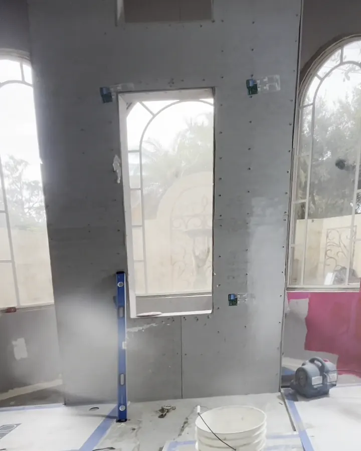 Window wall mid-job, with gray board and red waterproofing