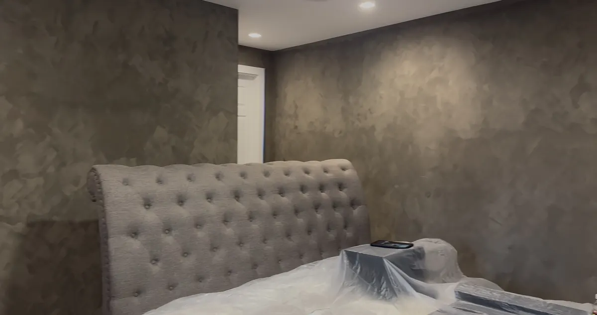 Dark textured wall finish behind a tufted headboard