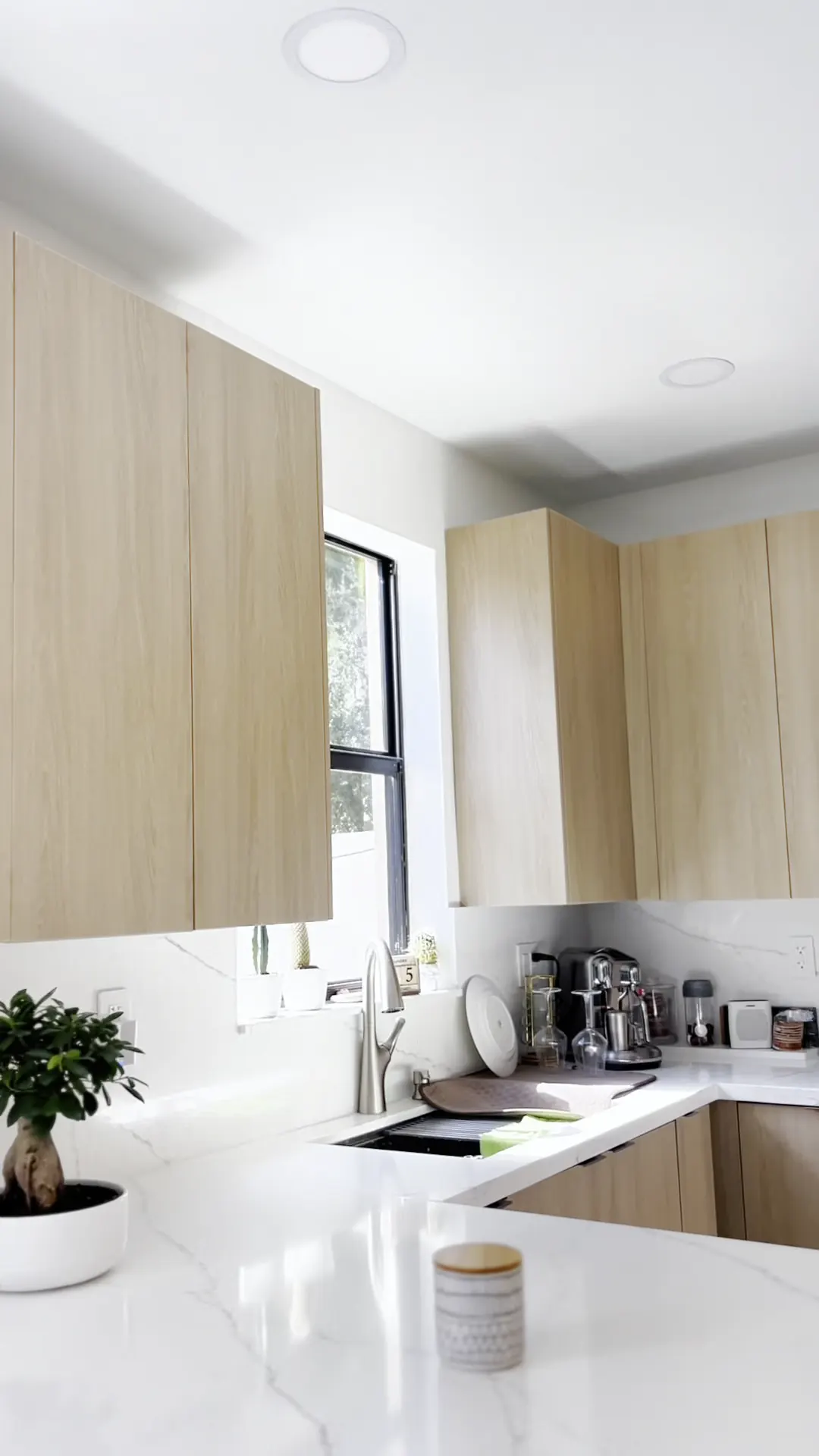 Light wood upper cabinets and a marble backsplash in a finished kitchen