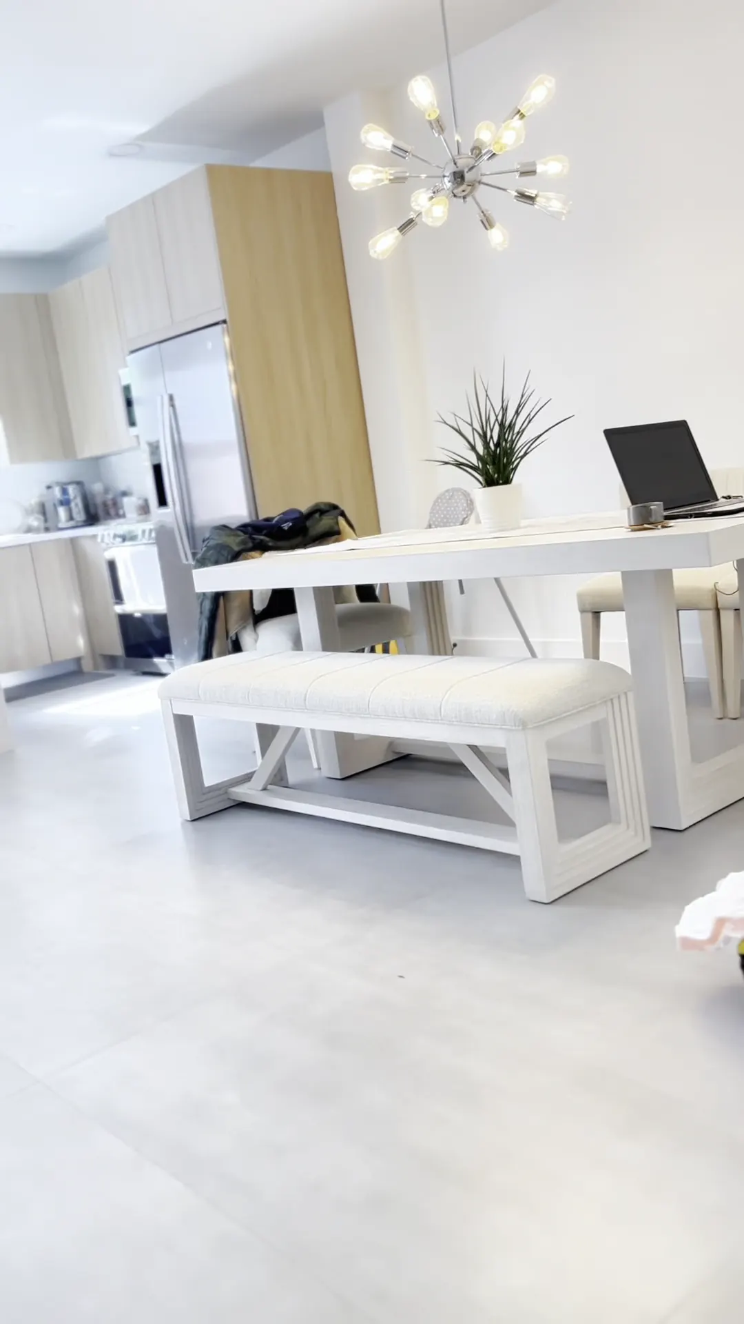 Dining area with a white table and bench on large light floor tiles