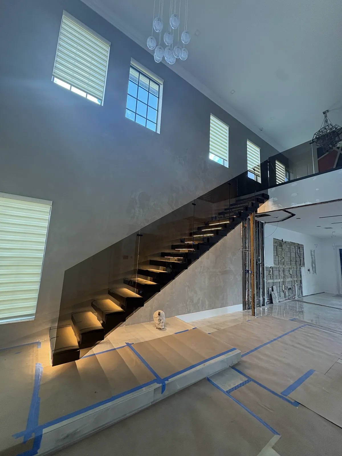 Two-story stair hall with textured grey walls and a floating staircase
