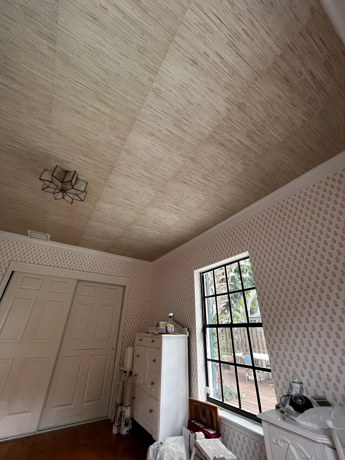 Grasscloth wallpaper on a sloped ceiling above patterned wallpaper walls