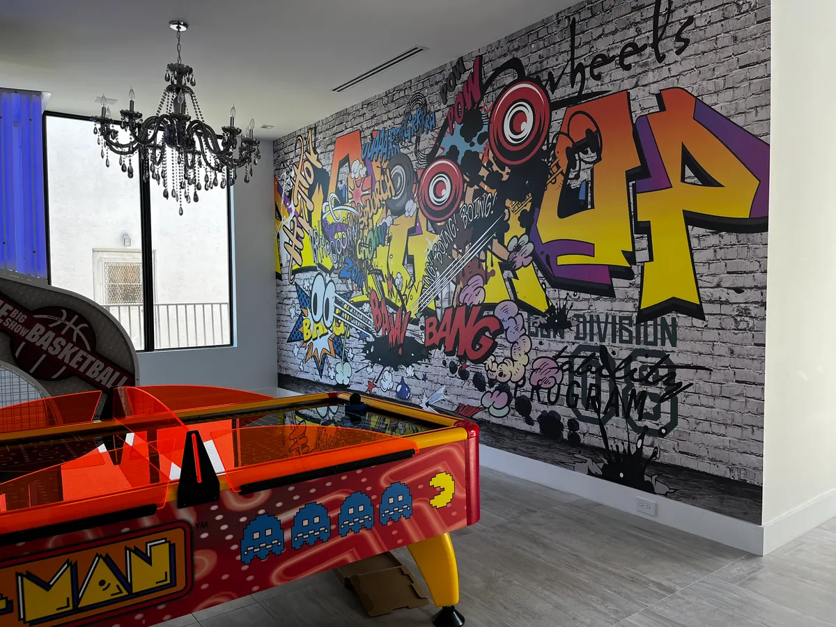 Game room with a graffiti mural wallpaper, a black chandelier and an air hockey table